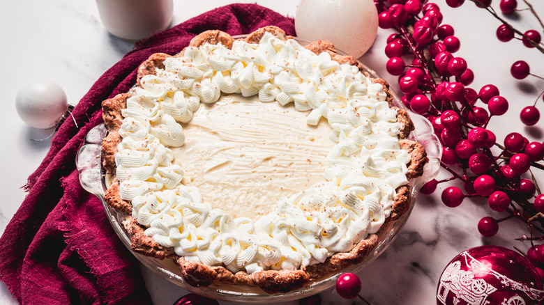 Old-fashioned eggnog pie with piping surrounded by Christmas decor