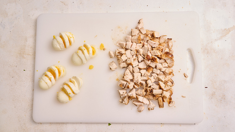 sliced hard boiled eggs and diced chicken on cutting board