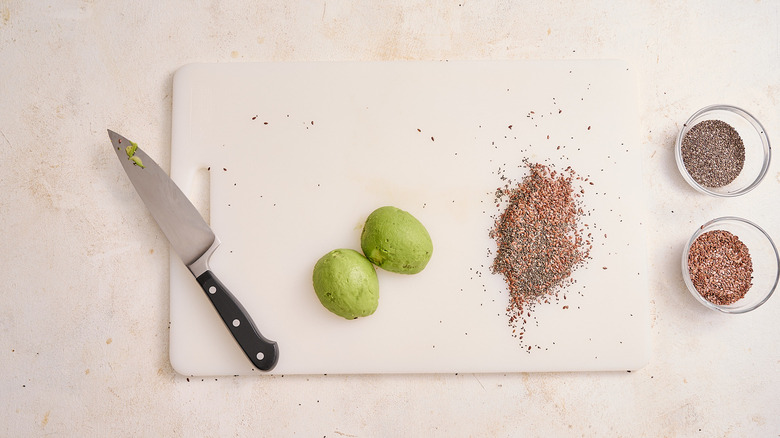 knife, peeled avocado, and seed mixture on cutting board
