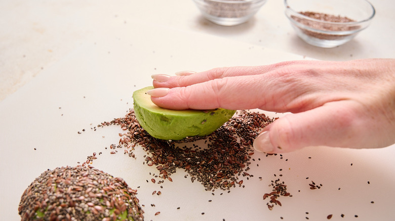 hand rolling avocado through seeds