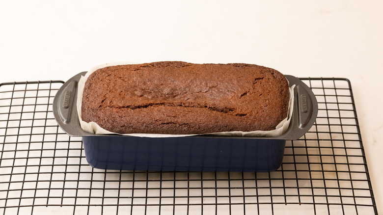 Baked loaf cake in pan sitting on wire rack