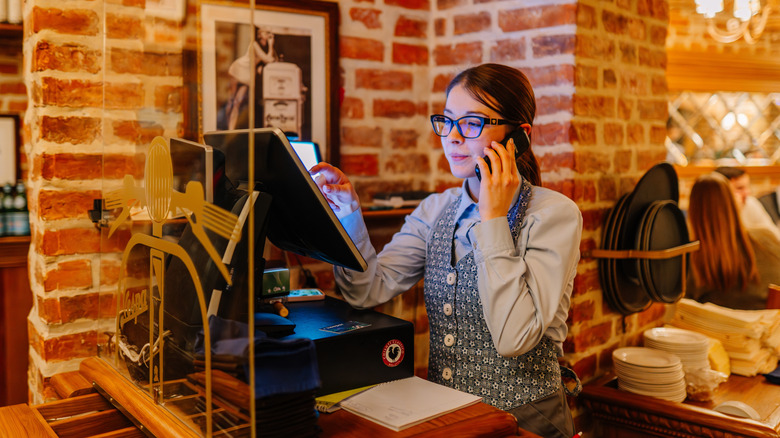 A hostess at a restaurant taking a reservation over the phone