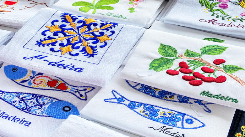 Several embroidered Madeira-themed kitchen towels laid out together