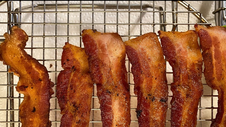 Strips of cooked bacon on a cooling rack over paper towels