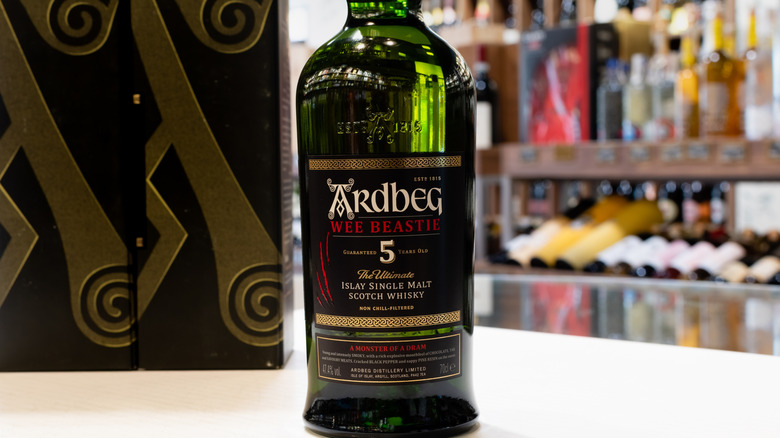 Bottle of Ardbeg Wee Beastie in a liquor store with bottles on shelves blurred in the background