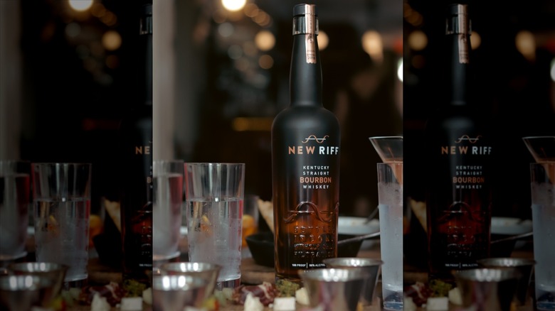 Bottle of New Riff Kentucky Straight Bourbon Whiskey on a table with food and drinks