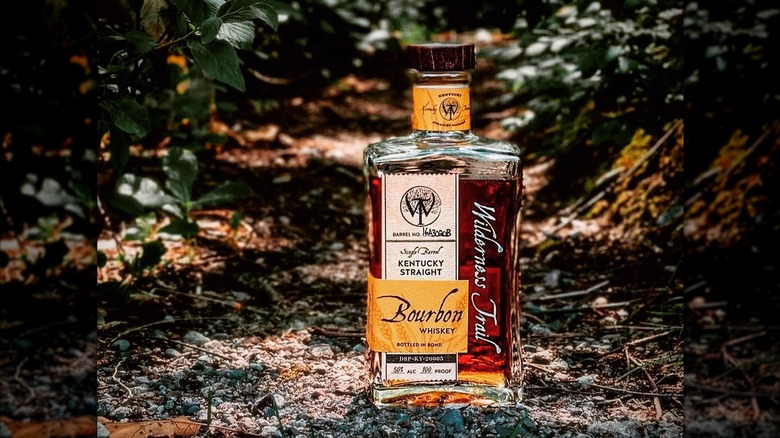 Bottle of Wilderness Trail Bourbon on the ground outdoors