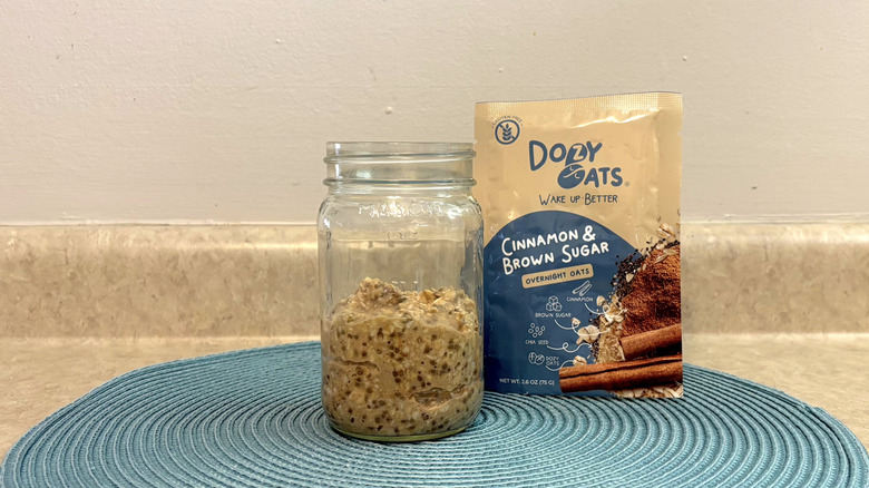 Dozy Oats cinnamon and brown sugar overnight oats mix in a mason jar on blue placemat, beige countertop