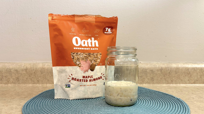 Oath Oats maple roasted almond overnight oats mix in a mason jar on blue placemat, beige countertop