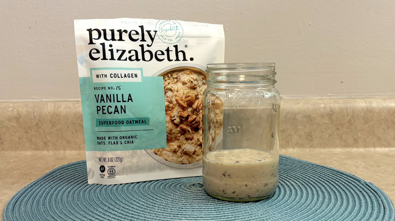 Purely Elizabeth vanilla pecan overnight oats mix in a mason jar on blue placemat, beige countertop