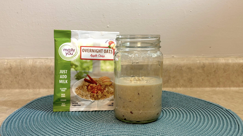 Molly & You apple crisp overnight oats mix in a mason jar on blue placemat, beige countertop