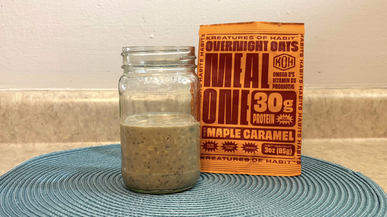 Kreatures of Habit maple caramel overnight oats mix in a mason jar on blue placemat, beige countertop