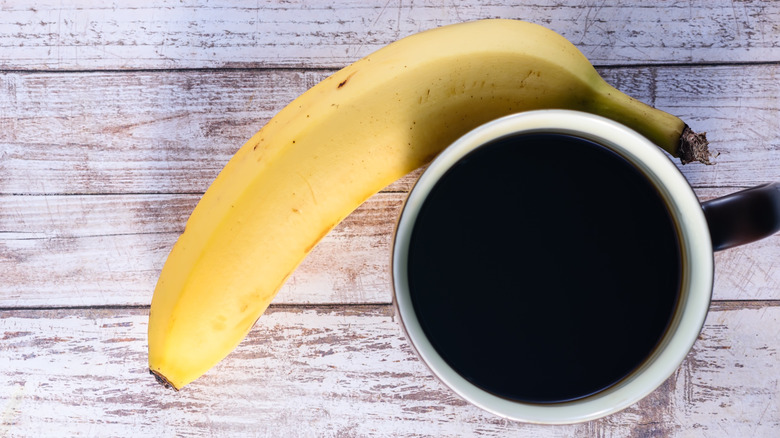 Cup of coffee and a banana on a wood table