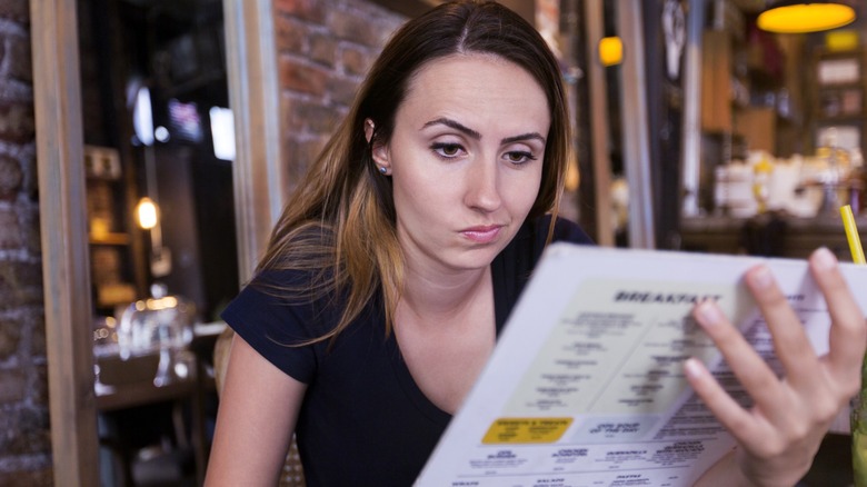 Woman looking unimpressed by a restaurant's menu offerings