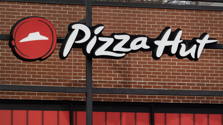 Sign on a brick wall above the front of a Pizza Hut restaurant