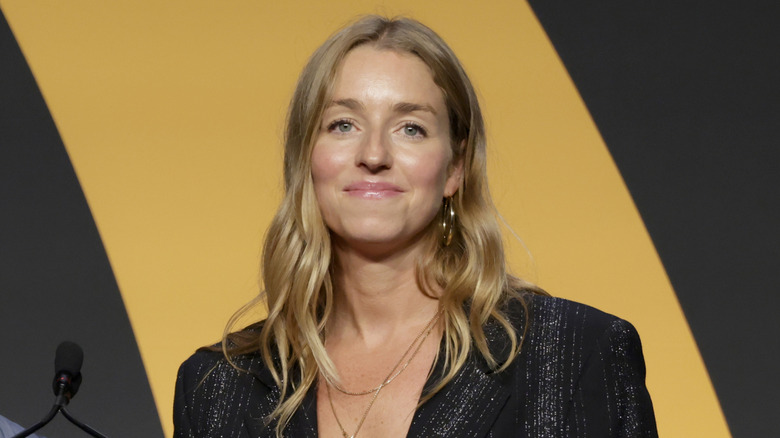 Molly Baz smiles in black blazer