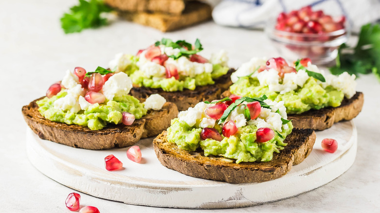 toast topped with avocado, cheese, and pomegranate seeds