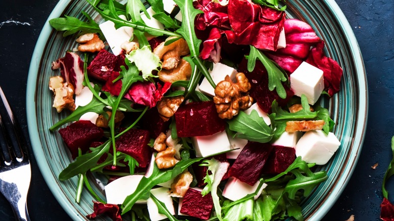 Top-down view of arugula, beet, cheese, and walnut salad