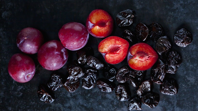 dried and fresh plums on black stone countertop
