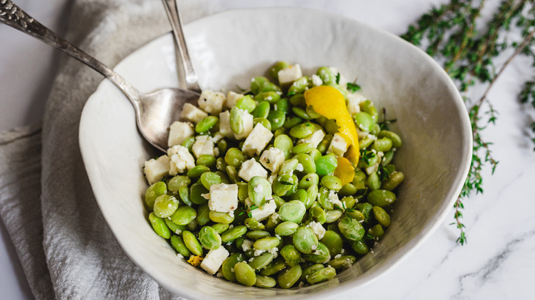 lima beans and feta in white bowl with two spoons