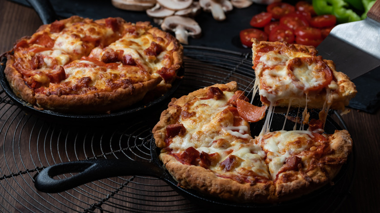Two pan pizzas in cast iron skillets on a table