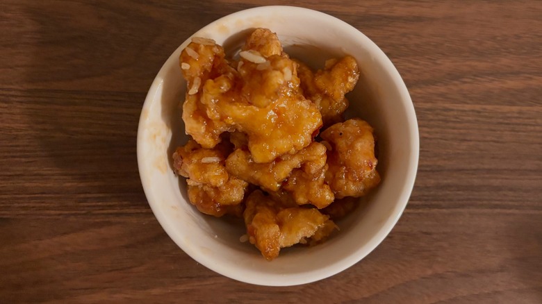 Small white bowl with top-down view of orange chicken