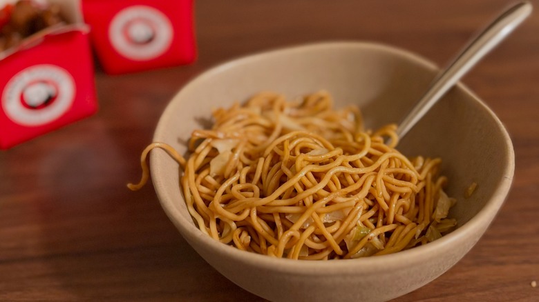 Bowl full of chow mein noodles with silver spoon