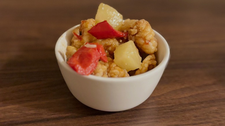 Small white bowl with chicken, peppers, and pineapple
