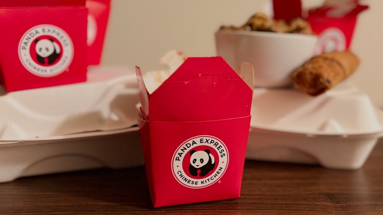 Panda Express red takeout box in front of food and other white takeout containers