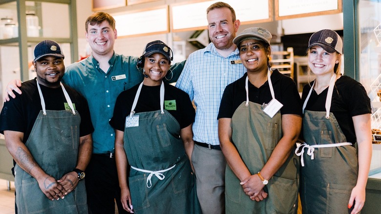 Six employees at Panera Bread restaurant posing in group for photo