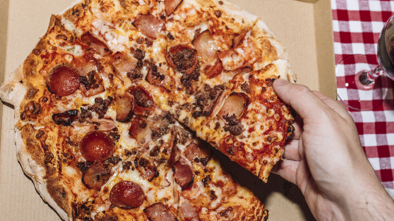 pepperoni pizza slice being lifted from whole pizza