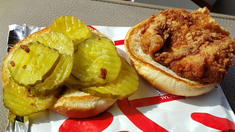 Two halves of a Chick-fil-A's chicken sandwich, one loaded with pickles