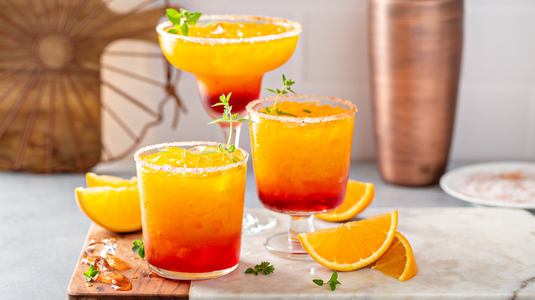 Three tequila sunrise cocktails in different style glasses