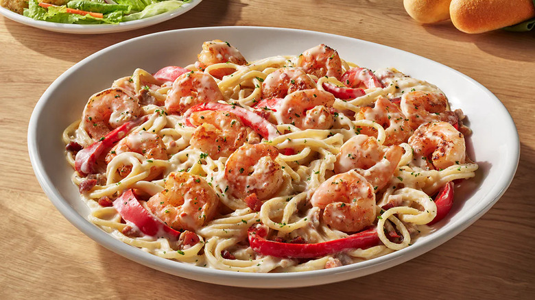 Olive Garden shrimp carbonara on a table with salad and breadsticks