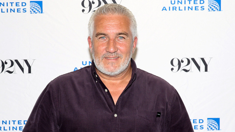 Paul Hollywood smiles in black button up shirt