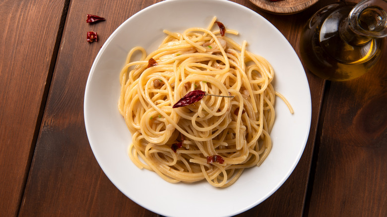 White bowl of pasta aglio e olio on a wooden table