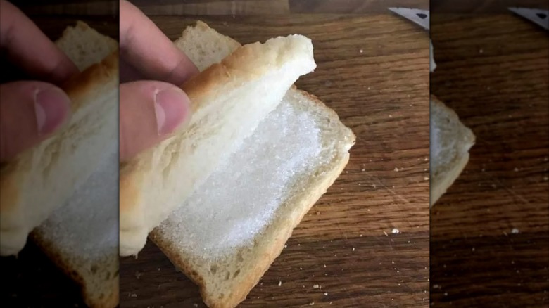 Mirrored image of a hand opening a sugar sandwich on a wooden table