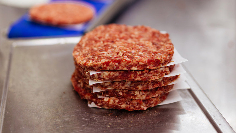 Stacks of raw burger patties on paper