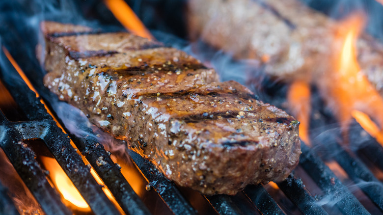 a seasoned sirloin steak cooking on a grill
