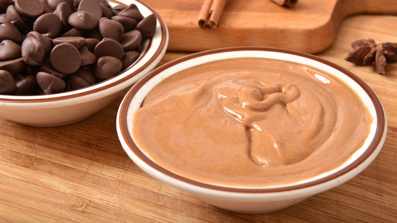 Small white bowls of peanut butter and chocolate chips on wooden surface