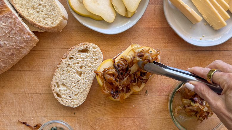 hand adding onions to sandwich
