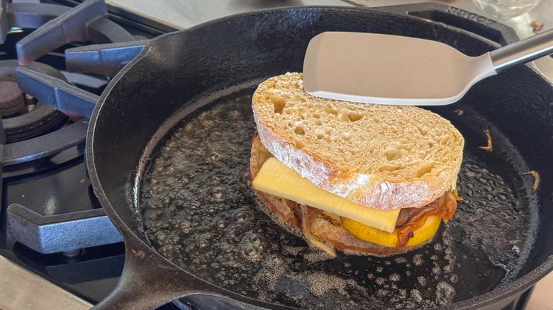 spatula pressing grilled cheese in skillet