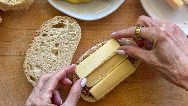hands adding cheese slices to bread