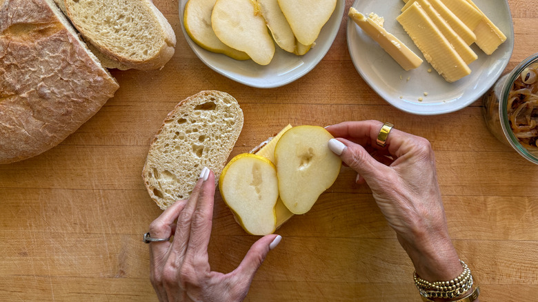 hand adding pear slices to bread