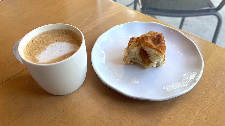 Partially drunk Starbucks Pecan Oatmilk Cortado next to half-eaten apple croissant