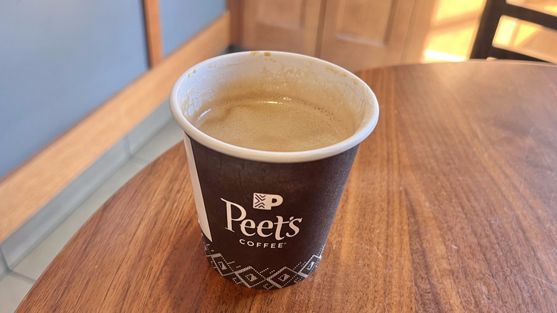 Small cup of cortado from Peet's on a wooden table