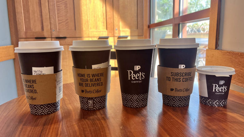 Several hot Peet's drinks on a wooden table in front of a window
