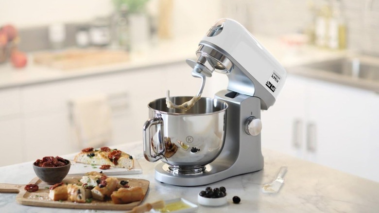 A Kenwood kMixer with the dough hook attached on a kitchen counter.