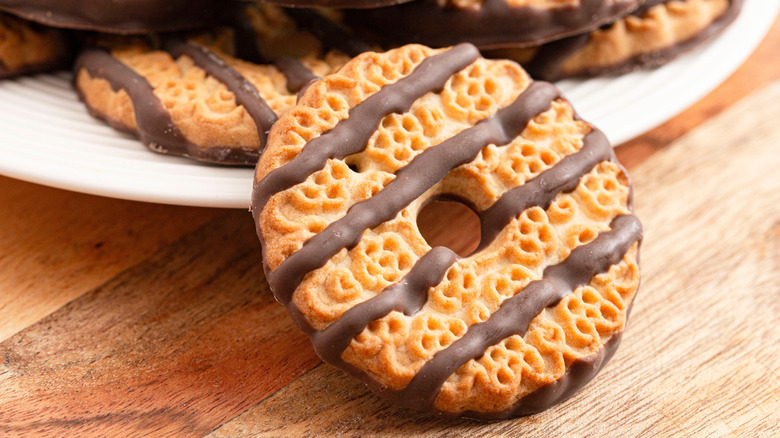 A plate of fudge-stripe cookies sits in the background with a single cookie balanced on the edge