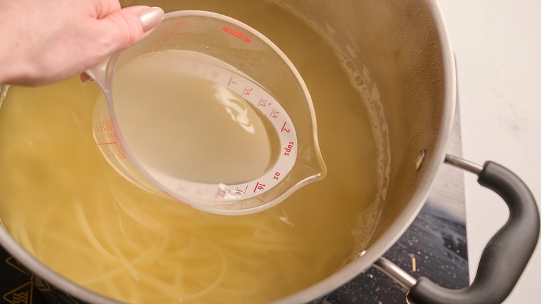 reserving pasta water with measuring cup